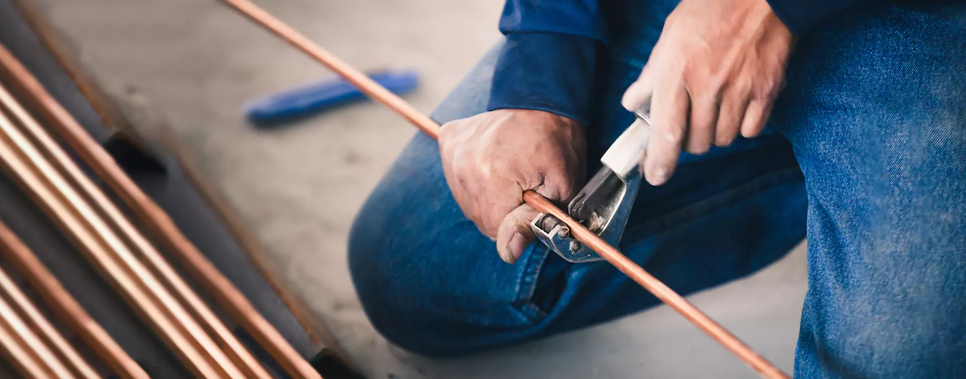 Person Cutting a Bronze Tube | HVAC Services